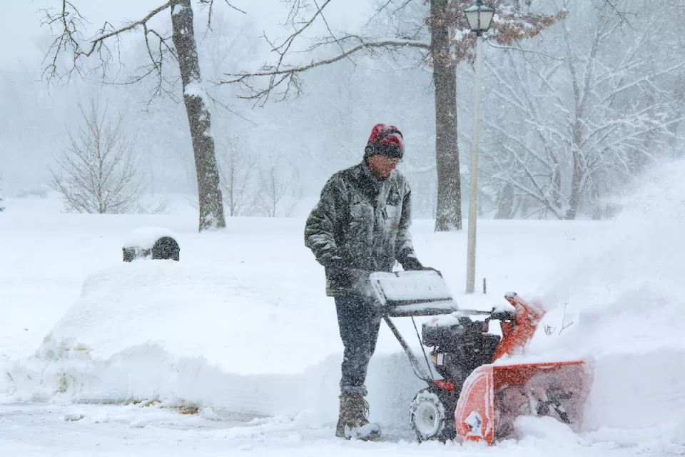 Man using snow plow during snowstorm.